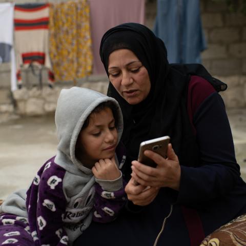 Nawal, a Syrian refugee and single mother of five, receives an SMS that she will receive winter cash assistance from UNHCR. She is pictured with her youngest daughter Raneem, 10, at home in Amman, Jordan.