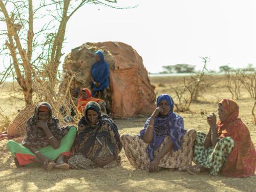 Ethiopian women sitting on the ground in a desert thinking 