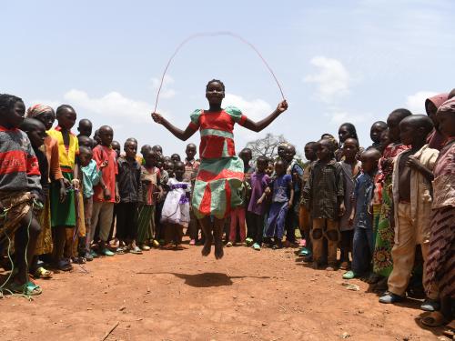 a young girl plays jump rope surrounded by her classmates.
