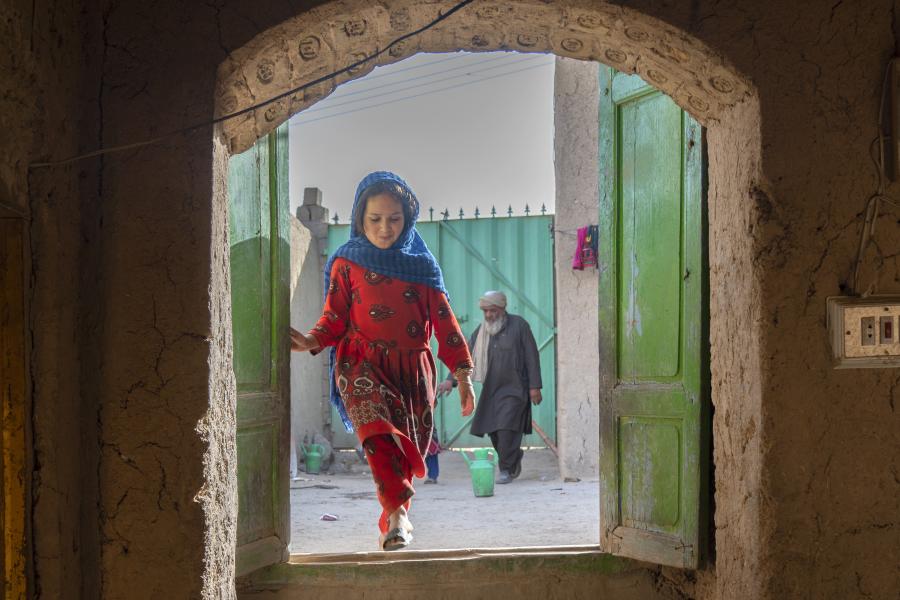 A young and joyful girl dressed in red runs down the stairs of a settlement for displaced people.