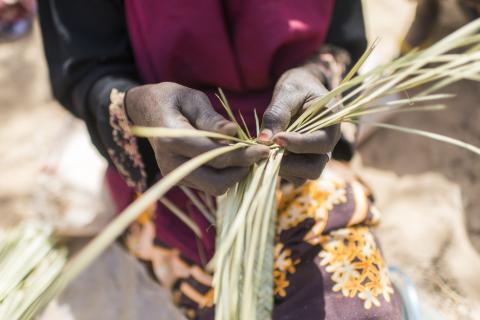 a lay making a mat from grasses