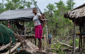 Venezuelan woman wearing a pink skirt is carrying her young son on her back