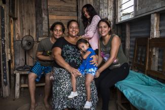 Family photo of a mother sitting with her son and three daughters surrounding her.