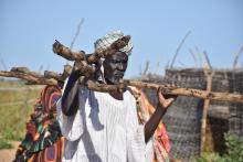 man carrying building poles