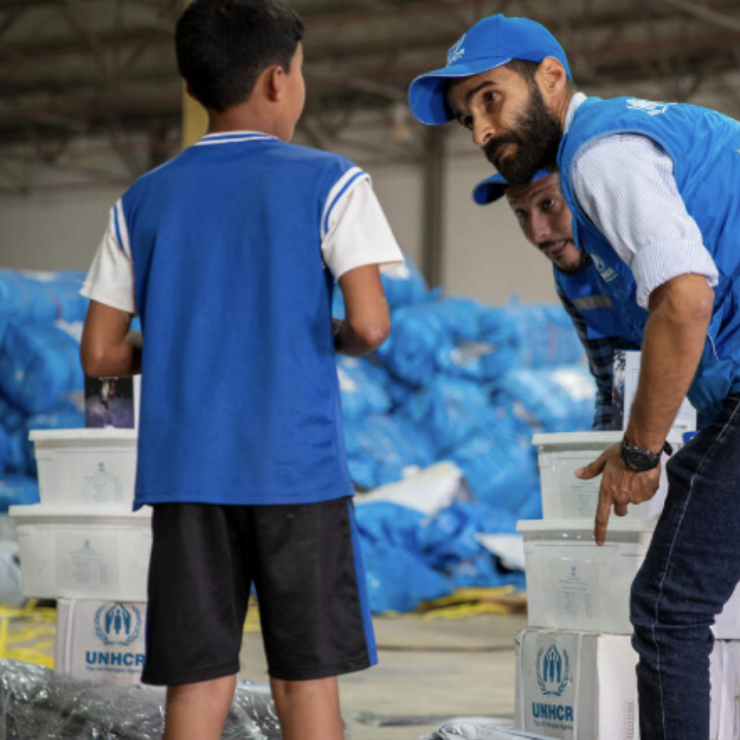 UNHCR staff distributing core relief items to a child