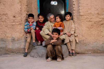 man sitting on a door step surrounded by kids