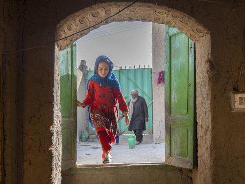 A young and joyful girl dressed in red runs down the stairs of a settlement for displaced people.