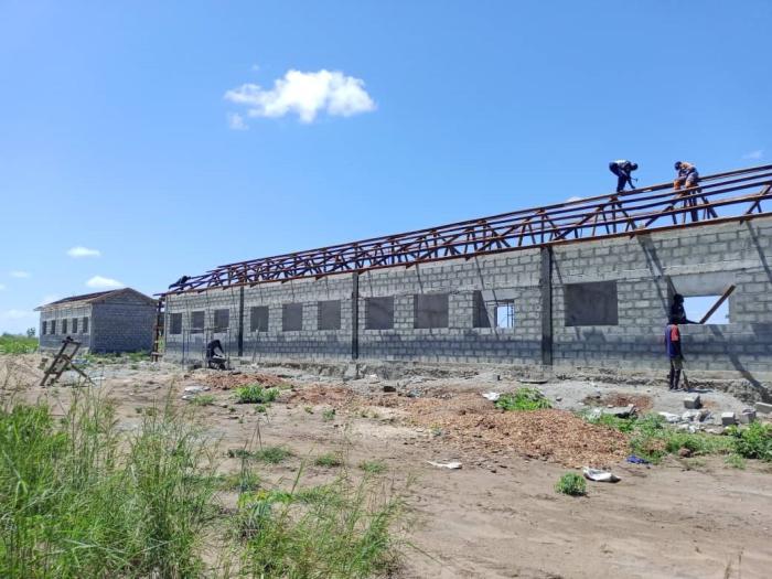 people putting a roof on classroom blocks