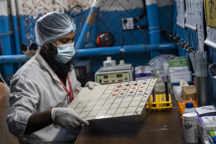 A person with white coat and other protective clothing looks at a lab chart.