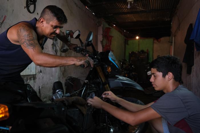 Douglas Rojas (15) with his father Luis David returned to Venezuela from Bogota in 2021, and they later moved to Peru before deciding to return to Venezuela in 2023. Currently, Douglas is participating in training for motorcycle repair, as his father has a motorcycle repair shop. © UNHCR/Santiago Escobar-Jaramillo