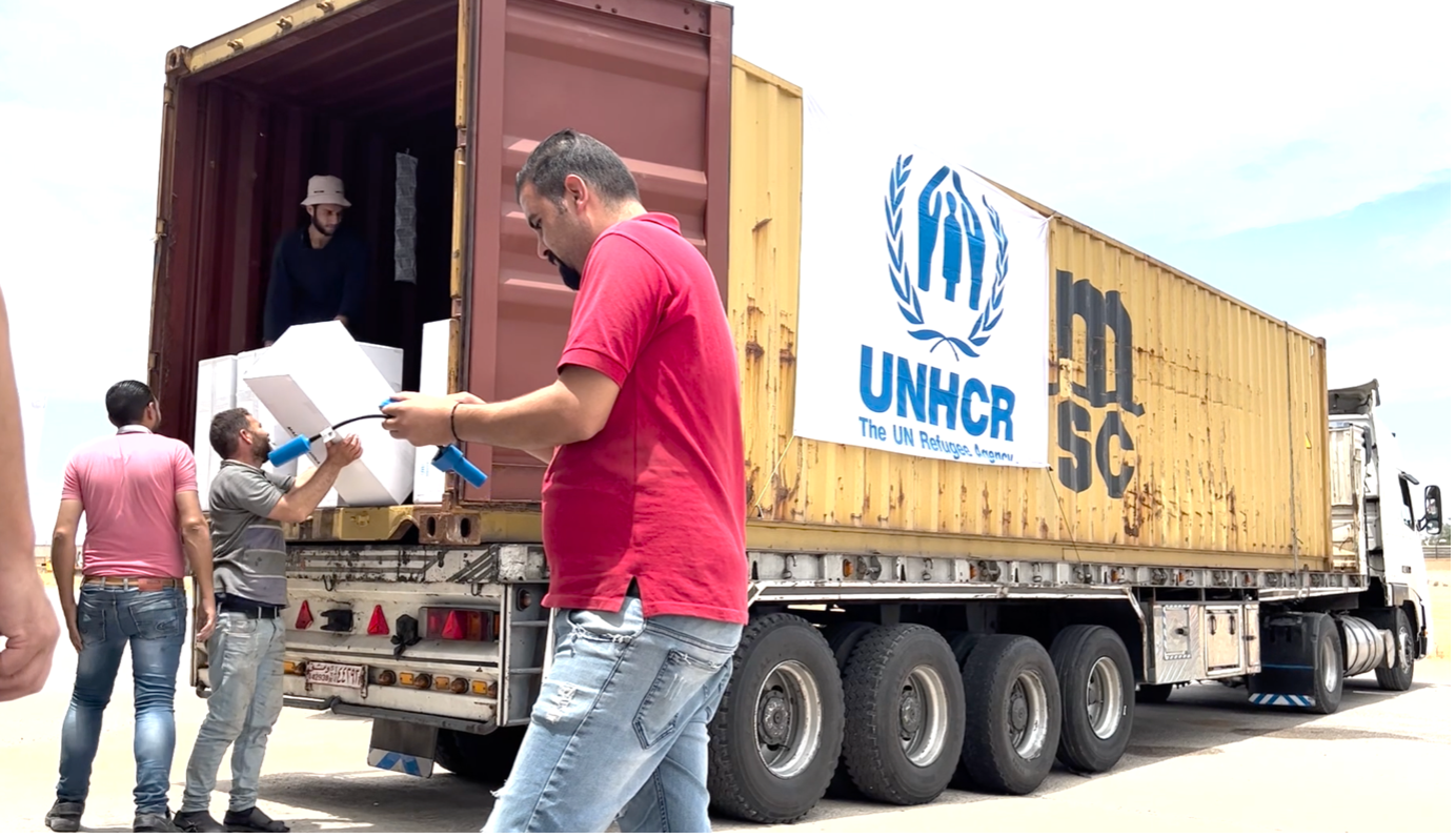 men carrying boxes on a UNHCR truck
