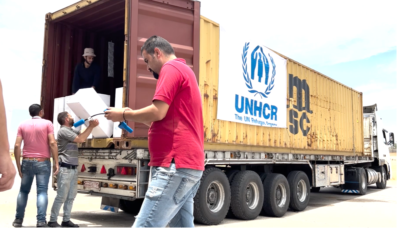 men carrying boxes on a UNHCR truck