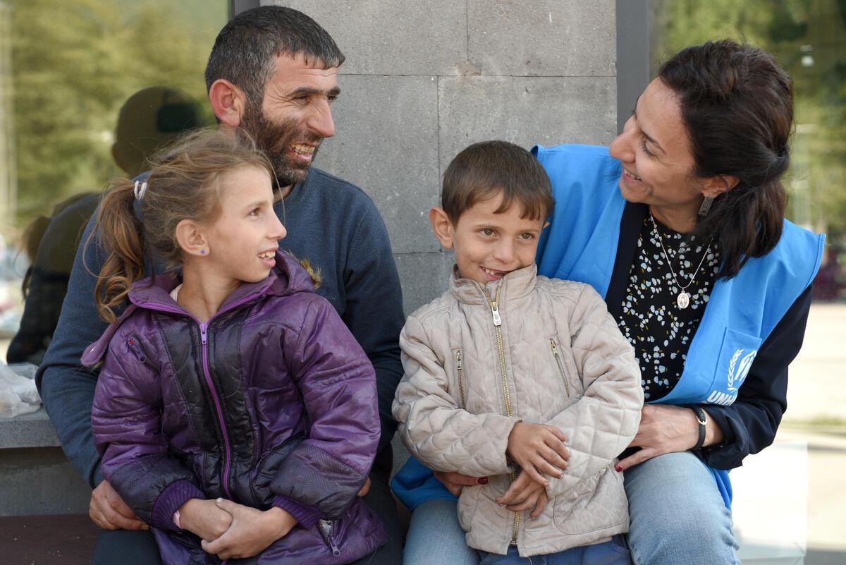 man and children talking to UNHCR staff