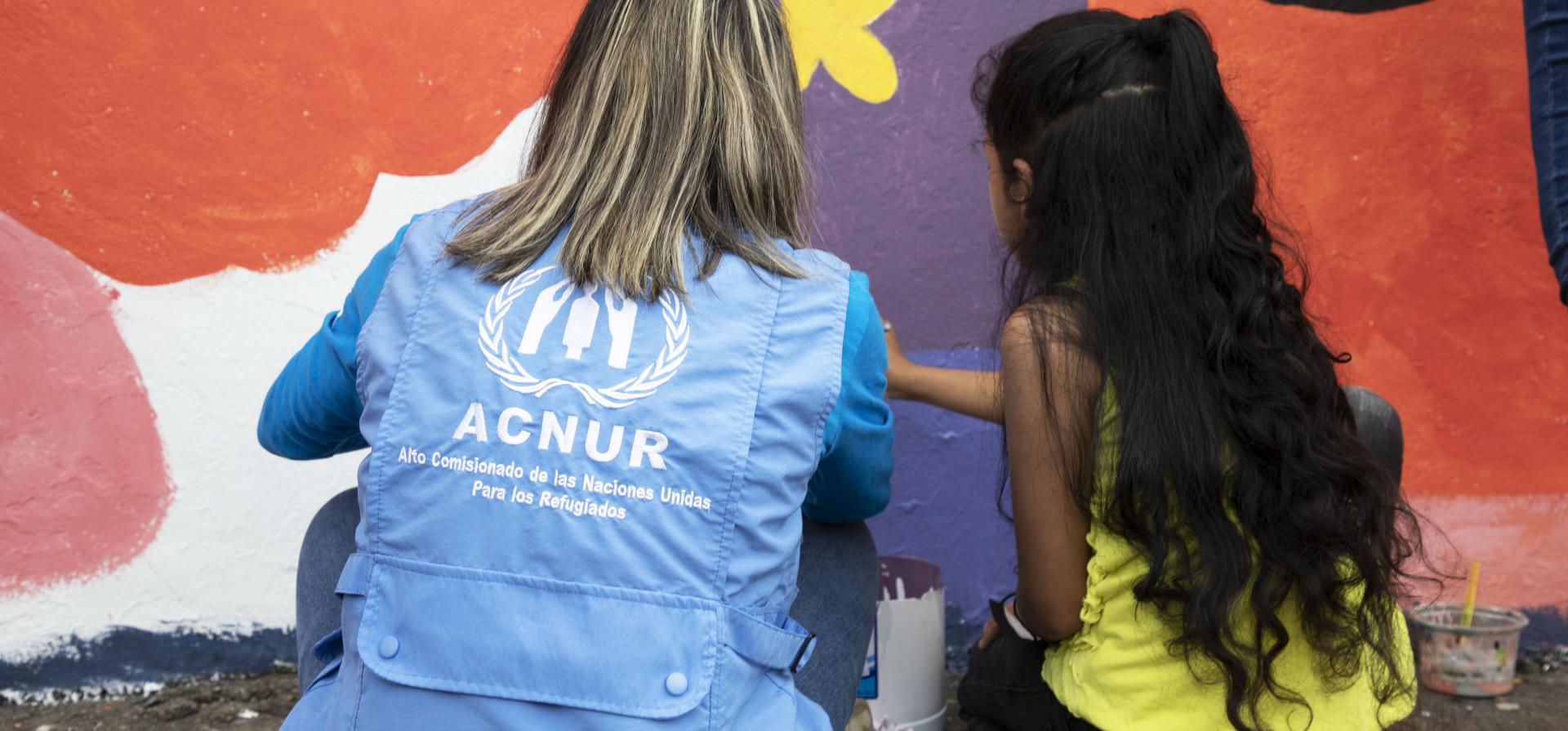 UNHCR staff painting with a child. 