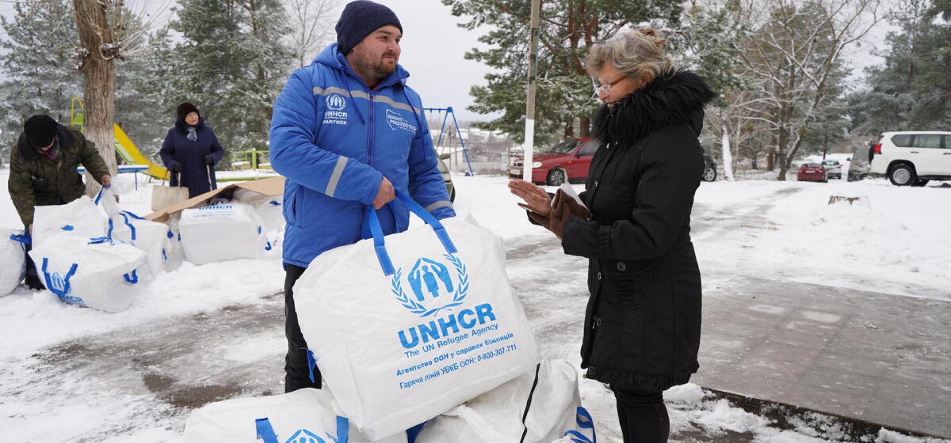man giving a bag of items to a woman during winter