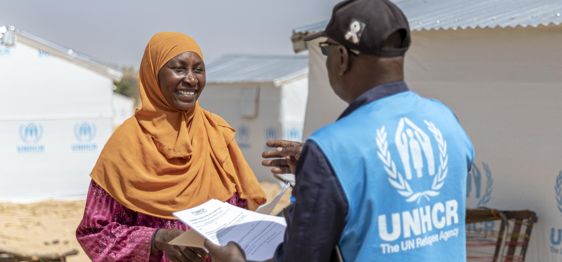 woman talking to UNHCR staff in a refugee site