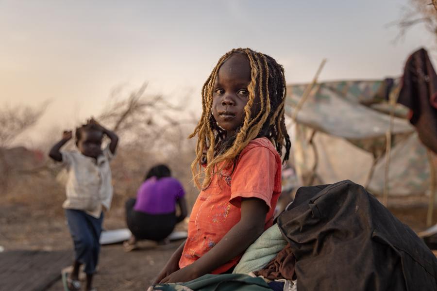Acel, 5, stands at her family's shelter in bushland outside the UNHCR transit centre in Renk, South Sudan, after her siblings and her mother fled from Khartoum, Sudan, and travelled for five days on trucks to reach the border.