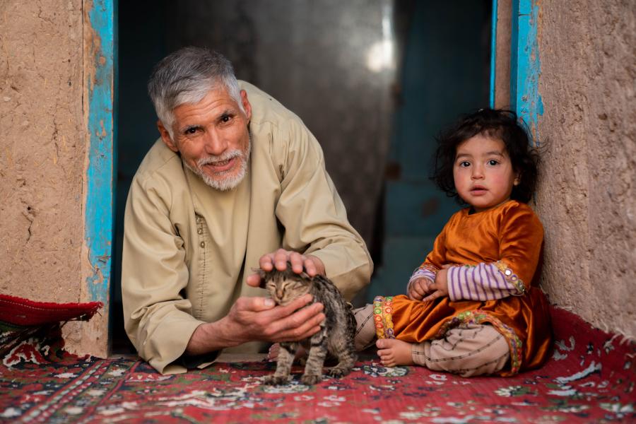 A man and a child sitting down playing with a cat