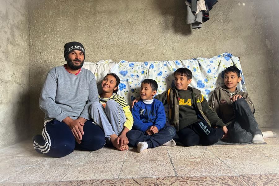 Isam sitting with his four children on a mattress in a room in his house which was partially damaged during the crisis in Syria.