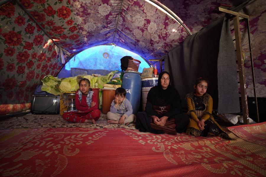 Woman siting with her children in their tent. 