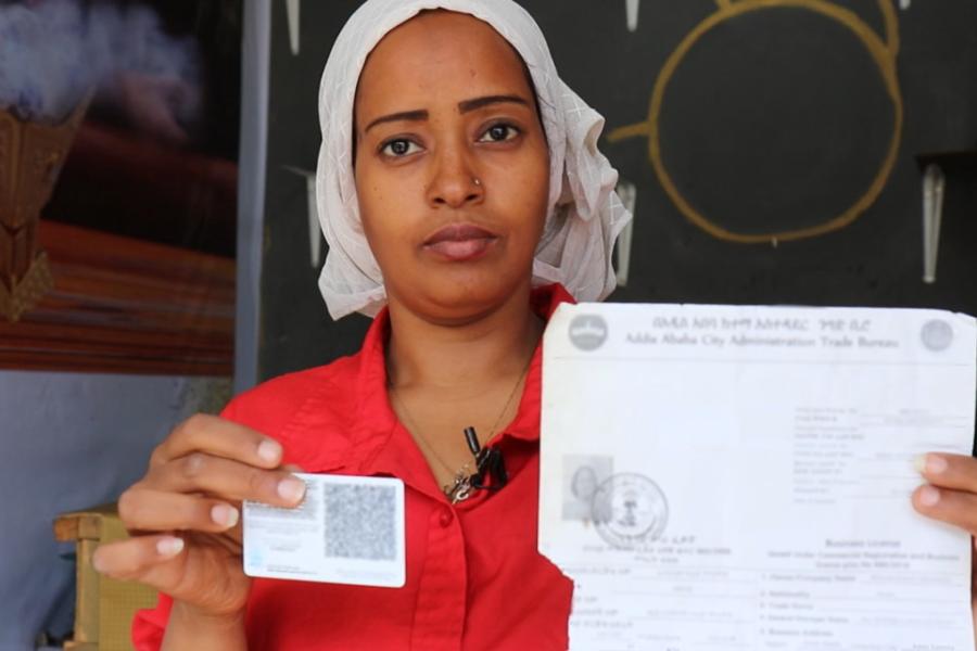 A woman showing business license and refugee national ID 