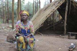 Emmanuelle, 56, from DRC and mother of eight sits outside the makeshift shelter where she slept for over a month after fleeing deadly violence in DRC's Ituri province in late May 2020.