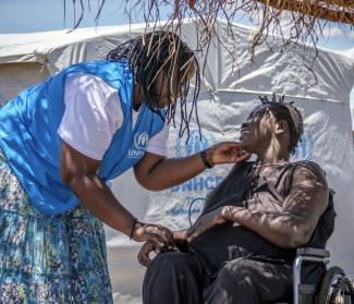 Grace Atim, Protection Officer of UNHCR, talks to Charity Gala, South Sudanese refugee with with special need at her home in Bidibidi refugee settlement in Yumbe district of Northern Uganda on 2 May 2017.