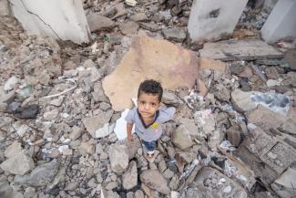 Adham stands in the rubble of a destroyed home in his old neighborhood in Yemen.