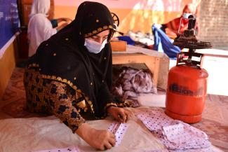 Shazia, 20, irons sheets of masks after being supported by UNHCR with a training in Nangarhar province of Afghanistan. 