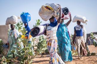 Malian Refugee women carry their belongings through Mbera refugee camp. 