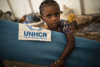 A young Ethiopian refugee collects a mattress at a transit site in Hamdayet, Sudan.