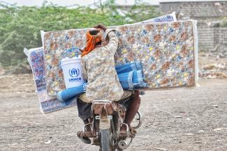 Internally displaced Yemenis carry home mattresses and other basic household items, following a UNHCR aid distribution in Hudaydah.