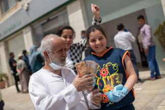 Ibrahim stands with his two youngest daughter Rora, 13, and Hala, 11, after collecting 100 dinar from the bank.