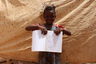 Malian refugee Zeinabou holds a school book in the shelter where she lives with her father, mother and sister in Ouallam camp, Niger. 
