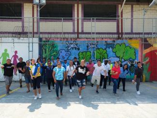 group of women and men happy in front of a murales